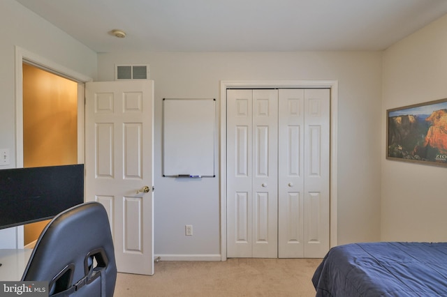 bedroom featuring light carpet, a closet, baseboards, and a desk