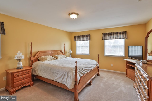bedroom with light colored carpet and baseboards