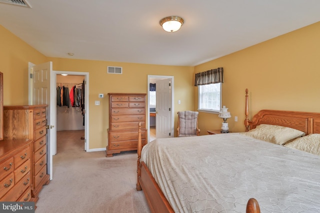 bedroom featuring light colored carpet, a walk in closet, a closet, and baseboards