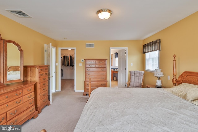 bedroom with a spacious closet, light colored carpet, a closet, and baseboards