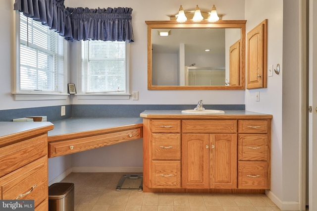 bathroom with a shower with door, vanity, tile patterned floors, and baseboards