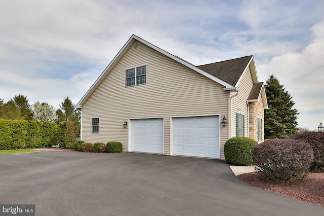 view of property exterior with driveway and roof with shingles