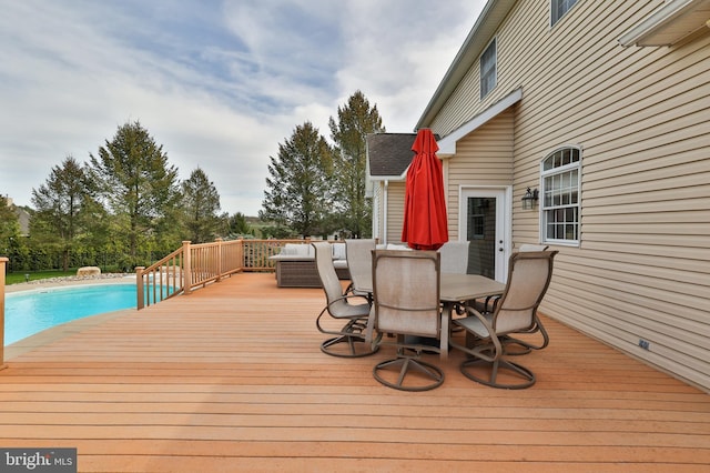 wooden terrace with an outdoor pool and outdoor dining area