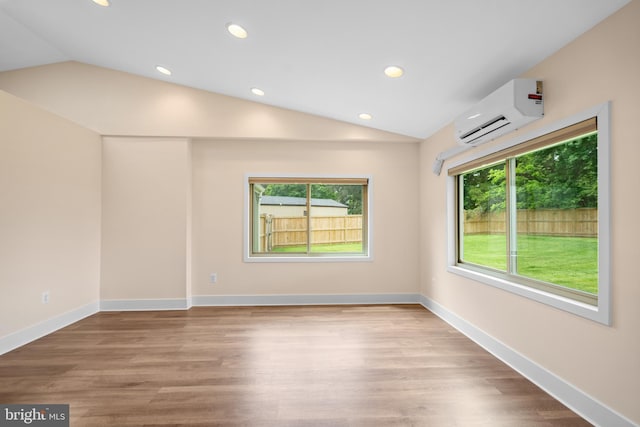 unfurnished room with lofted ceiling, a wall unit AC, recessed lighting, wood finished floors, and baseboards