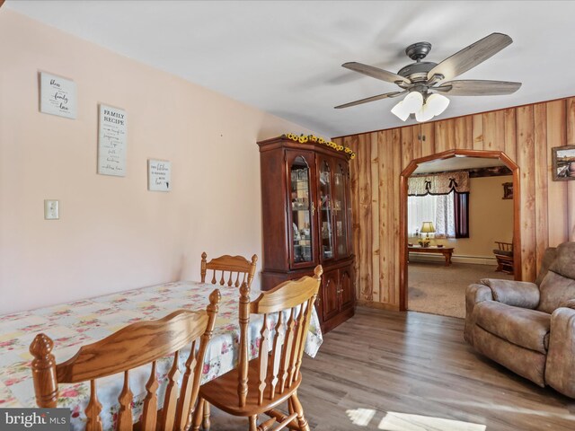 4126 Coseytown Rd, Greencastle, PA 17225 - dining area featuring arched walkways, wooden walls, a ceiling fan, and light wood-type flooring