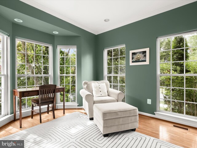 sitting room featuring light wood-type flooring, baseboards, and ornamental molding