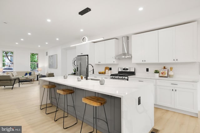 1404 Montello Ave NE, Washington, DC 20002 - kitchen featuring wall chimney exhaust hood, appliances with stainless steel finishes, a sink, light wood-style floors, and white cabinets