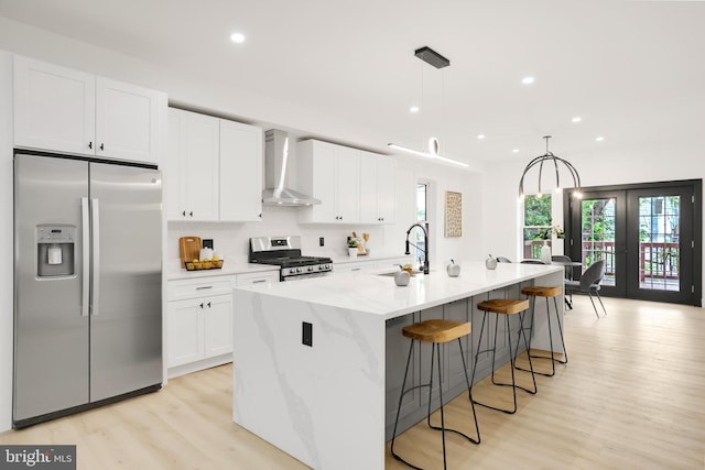 1404 Montello Ave NE, Washington, DC 20002 - kitchen featuring stainless steel appliances, wall chimney range hood, a sink, light wood-style flooring, and white cabinetry