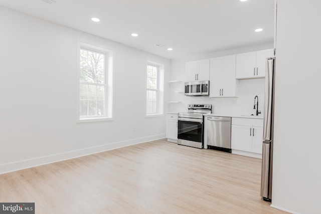1801 Otis St NE Unit 6, Washington, DC 20018 - kitchen with stainless steel appliances, light wood-style flooring, white cabinets, tasteful backsplash, and recessed lighting