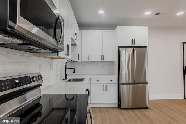 1801 Otis St NE Unit 6, Washington, DC 20018 - kitchen with stainless steel appliances, light countertops, white cabinetry, light wood finished floors, and backsplash