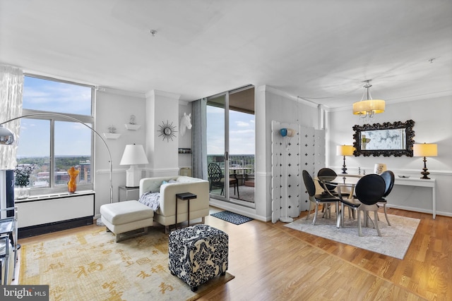 living room with ornamental molding, wood finished floors, a chandelier, and floor to ceiling windows