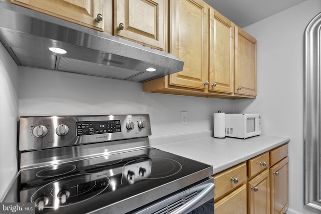 kitchen with stainless steel electric stove, extractor fan, white microwave, and light countertops