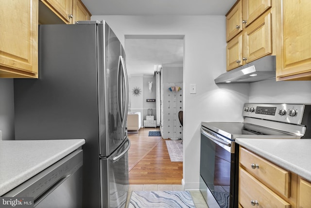 kitchen featuring stainless steel appliances, under cabinet range hood, light countertops, light brown cabinetry, and light wood finished floors