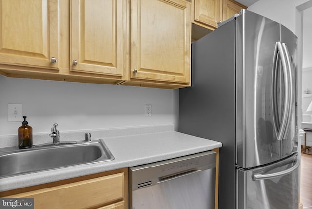 kitchen with appliances with stainless steel finishes, a sink, light brown cabinetry, light countertops, and wood finished floors
