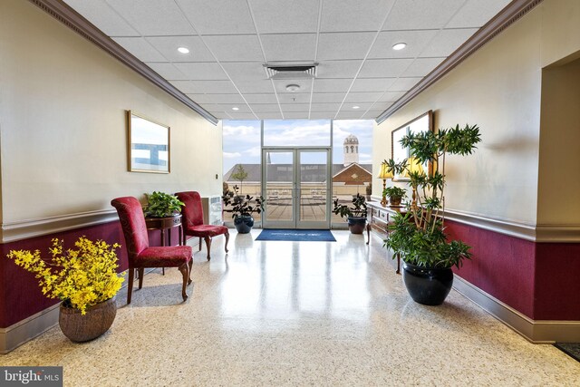 lobby with wainscoting, floor to ceiling windows, a drop ceiling, and recessed lighting