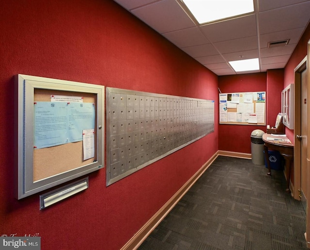 corridor with mail area, a paneled ceiling, carpet floors, and baseboards