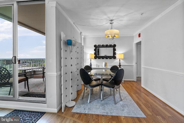dining area with wood finished floors, crown molding, baseboards, and a chandelier