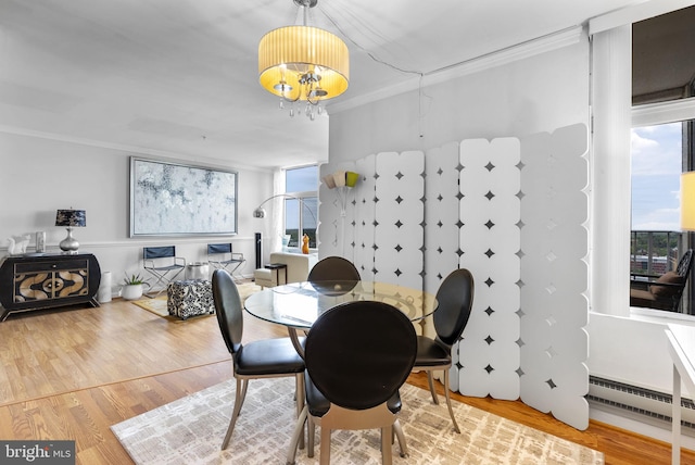 dining space featuring crown molding, a chandelier, wood finished floors, and a baseboard heating unit