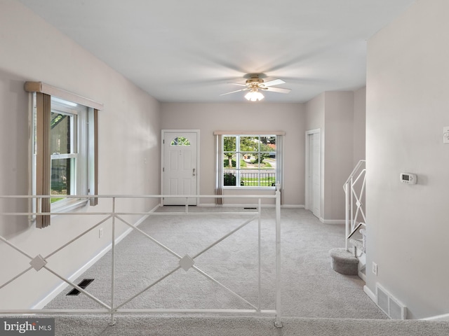 carpeted entryway featuring ceiling fan and baseboards