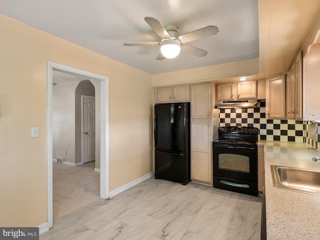 kitchen with black appliances, under cabinet range hood, a sink, light countertops, and decorative backsplash