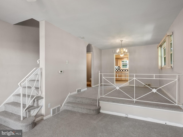 stairway with a chandelier, carpet flooring, baseboards, and arched walkways