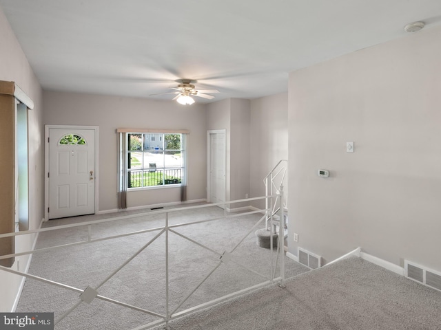 carpeted entryway with ceiling fan and baseboards
