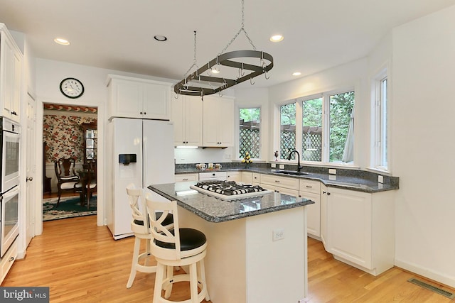 8265 Private Ln, Annandale, VA 22003 - kitchen featuring white appliances, a sink, light wood-style floors, white cabinetry, and a kitchen island