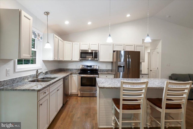 kitchen featuring stainless steel appliances, a sink, vaulted ceiling, light stone counters, and recessed lighting