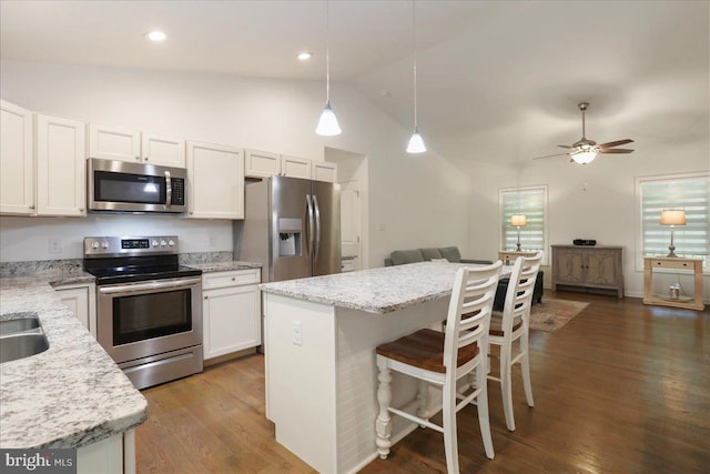 kitchen with stainless steel appliances, open floor plan, white cabinets, wood finished floors, and a breakfast bar area