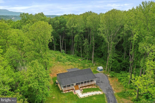 aerial view of property and surrounding area featuring a heavily wooded area