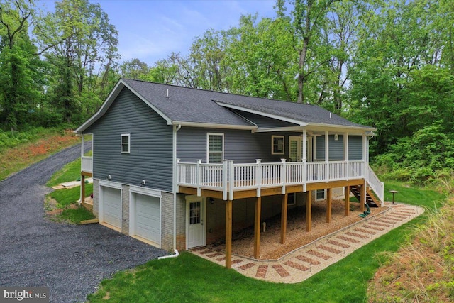 rear view of house with stairway, driveway, a shingled roof, a deck, and a garage