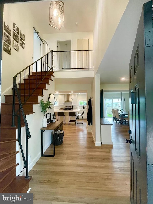 foyer entrance with stairway, wood finished floors, a high ceiling, and baseboards