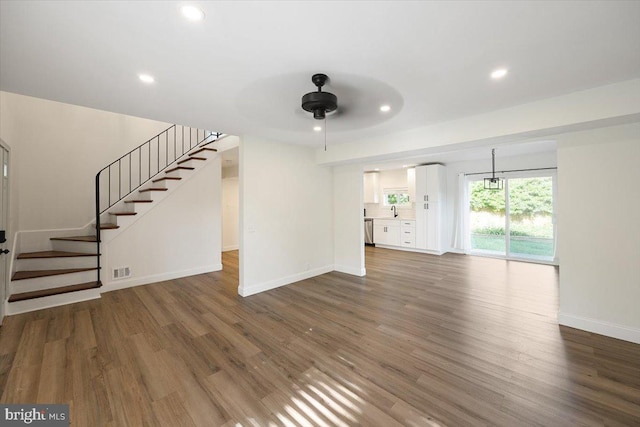 unfurnished living room with a ceiling fan, baseboards, dark wood-style flooring, stairway, and recessed lighting