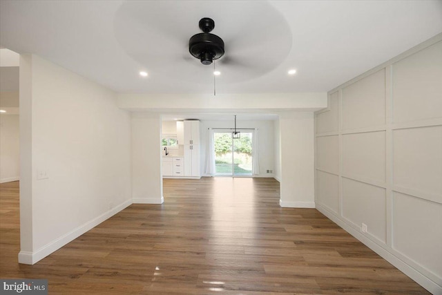 unfurnished room featuring a ceiling fan, wood finished floors, recessed lighting, baseboards, and a decorative wall