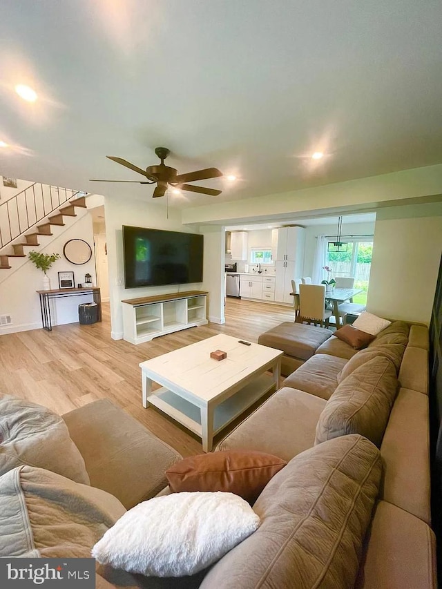 living area with stairs, ceiling fan, wood finished floors, and baseboards