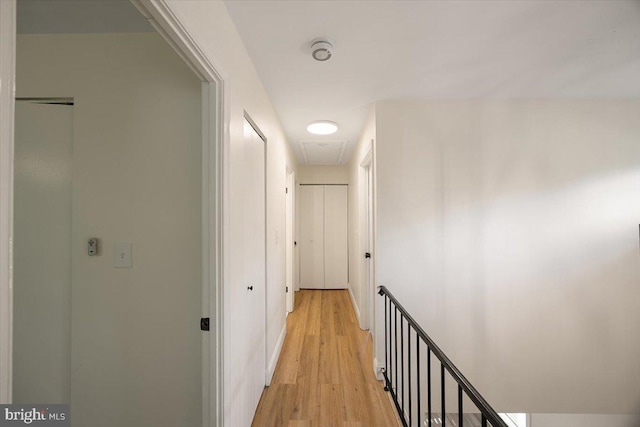 hallway featuring attic access, light wood finished floors, and an upstairs landing