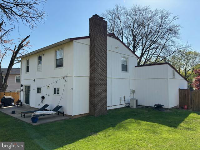 back of house featuring a patio area, a chimney, and cooling unit