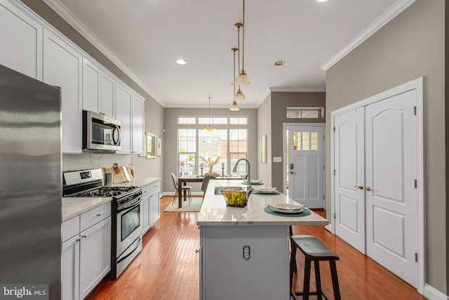 3911 Fleet St, Baltimore, MD 21224 - kitchen with stainless steel appliances, light wood-type flooring, an island with sink, a kitchen bar, and crown molding