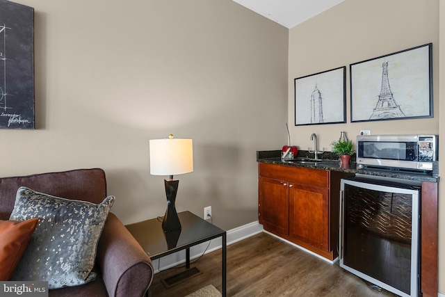 3911 Fleet St, Baltimore, MD 21224 - indoor wet bar featuring stainless steel microwave, beverage cooler, dark wood finished floors, and baseboards