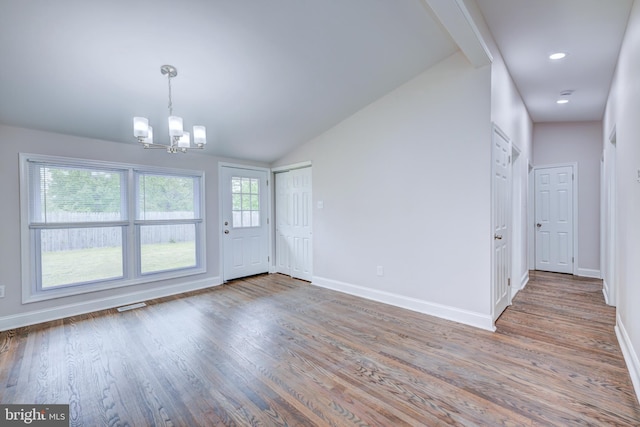 unfurnished dining area featuring a chandelier, baseboards, wood finished floors, and vaulted ceiling
