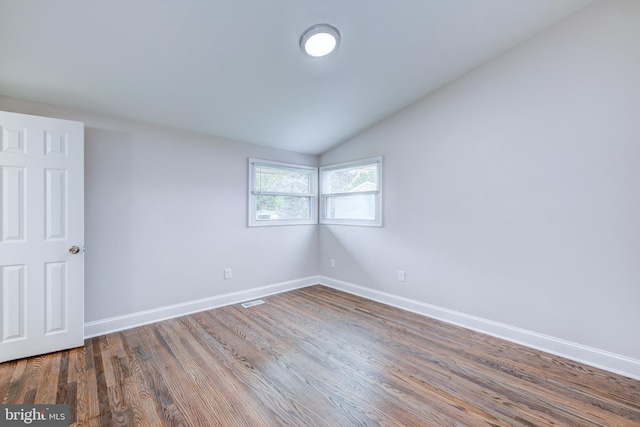 unfurnished room featuring wood finished floors, baseboards, and vaulted ceiling