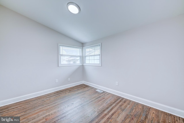 spare room with wood finished floors, baseboards, and vaulted ceiling