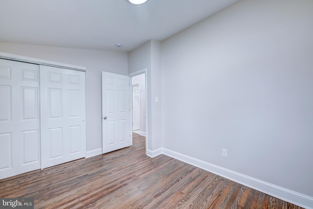 unfurnished bedroom with wood finished floors, baseboards, and a closet