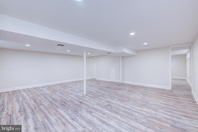 finished below grade area featuring light wood finished floors, recessed lighting, and baseboards