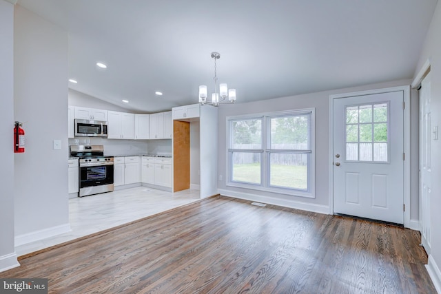 kitchen with appliances with stainless steel finishes, a chandelier, light wood finished floors, vaulted ceiling, and white cabinets