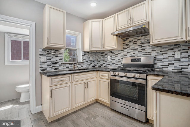 128 Linton St, Philadelphia, PA 19120 - kitchen featuring stainless steel gas range oven, under cabinet range hood, a sink, cream cabinetry, and backsplash