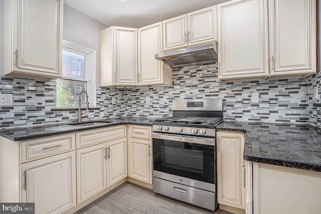 128 Linton St, Philadelphia, PA 19120 - kitchen featuring stainless steel gas range oven, a sink, under cabinet range hood, cream cabinets, and tasteful backsplash