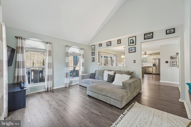 living area featuring wood finished floors, a ceiling fan, baseboards, and high vaulted ceiling