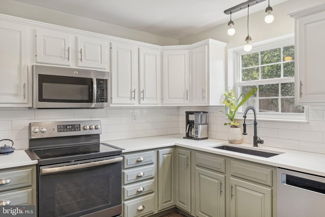kitchen with appliances with stainless steel finishes, a sink, light countertops, backsplash, and white cabinets