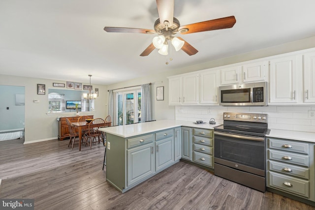 kitchen with appliances with stainless steel finishes, a peninsula, white cabinets, and tasteful backsplash